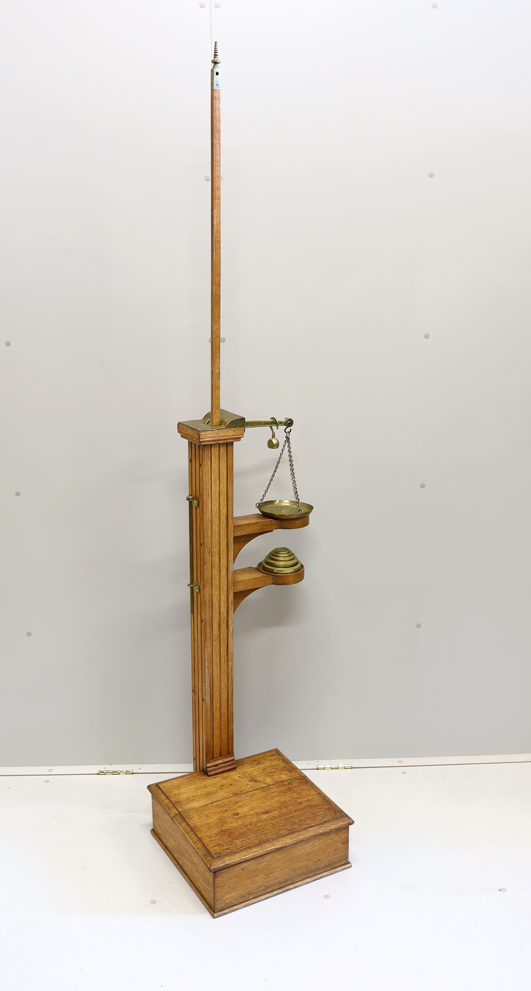 A Youngs of Bear St. London Victorian brass mounted oak personal weighing scales with incorporated height measuring stick, oak body and platform and set of five weights, 122cm